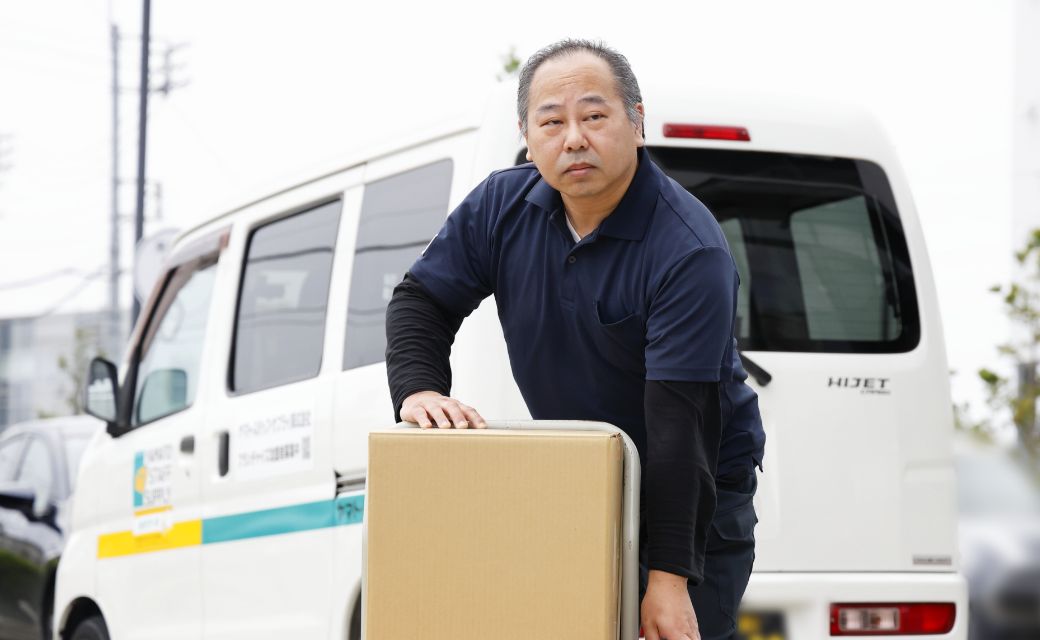 配送車両のそばで、台車を使ってテキパキと荷物を運搬するI.M.さん
