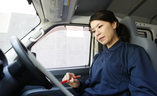 配送車を停め、車内で書類に記入している様子